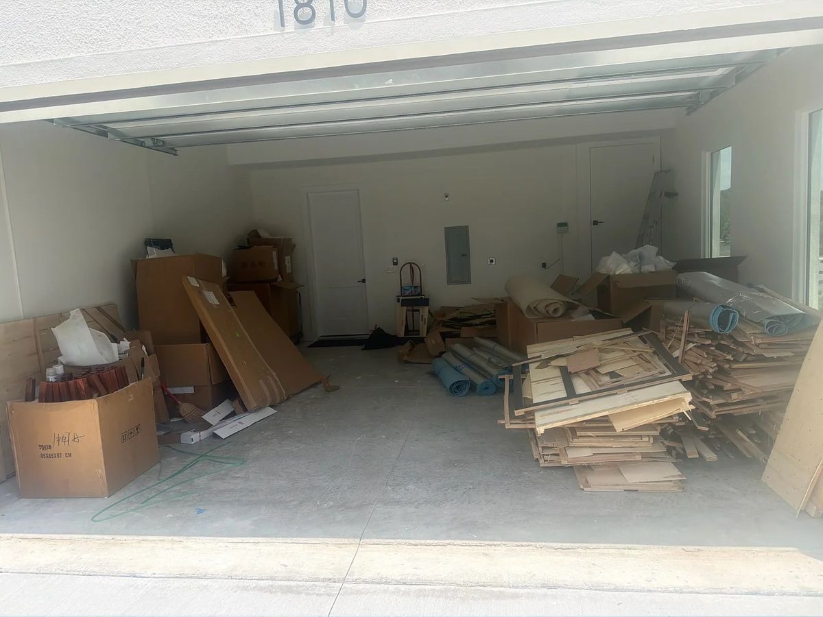 Two-car garage in Ocala packed with moving boxes, cardboard and trim scraps before a garage cleanout
